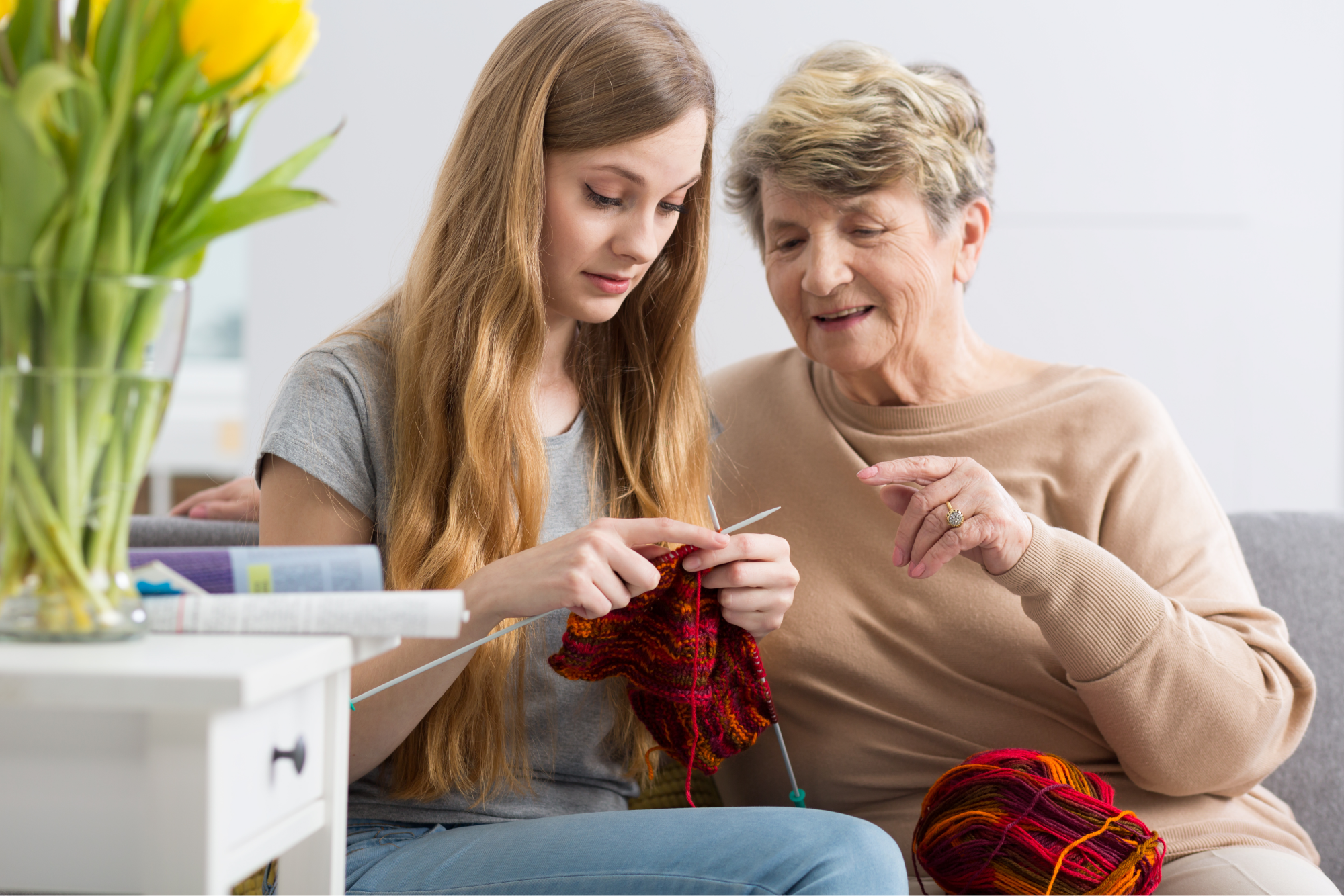 A young female senior companion knitting with an older woman