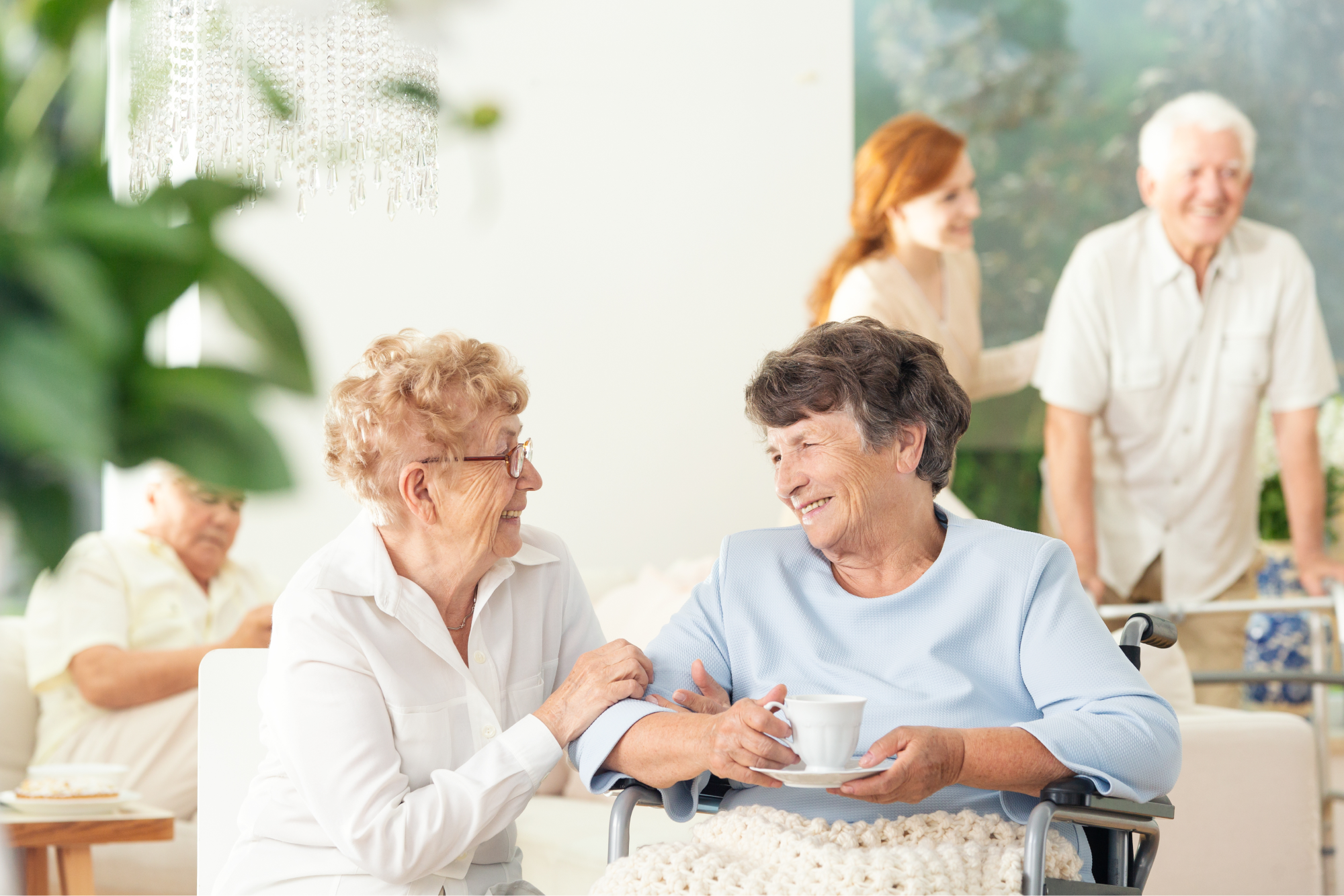 Two senior-aged women smiling and embracing each other while sitting