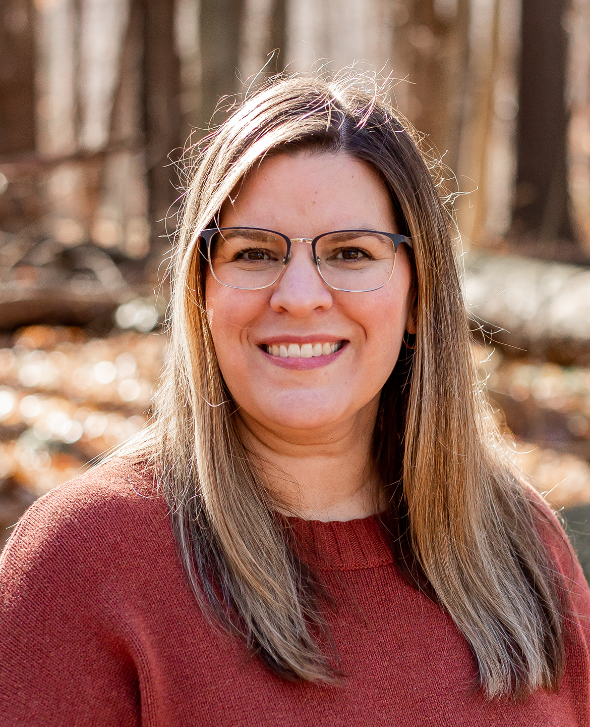 Amanda Redding smiling at the camera, standing in front of a large cliff and oceanside